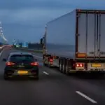 Επιβατικό αυτοκίνητο και φορτηγό κινούνται δίπλα δίπλα σε αυτοκινητόδρομο της Ολλανδίας το σούρουπο.