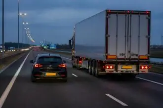 Επιβατικό αυτοκίνητο και φορτηγό κινούνται δίπλα δίπλα σε αυτοκινητόδρομο της Ολλανδίας το σούρουπο.