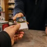Πελάτης παραλαμβάνει πακέτο τσιγάρων στον πάγκο μικρού καταστήματος στη Γερμανία.