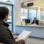 Άτομο με φάκελο εγγράφων σε χώρο εξυπηρέτησης αιτήσεων διαμονής στην Ολλανδία.