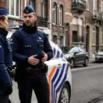 Δύο ένστολοι αστυνομικοί δίπλα σε περιπολικό σε αστικό δρόμο των Βρυξελλών.