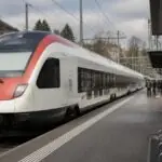 Επιβατικό τρένο με λευκό και κόκκινο χρωματισμό σε σιδηροδρομική αποβάθρα στην Ελβετία