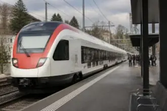 Επιβατικό τρένο με λευκό και κόκκινο χρωματισμό σε σιδηροδρομική αποβάθρα στην Ελβετία