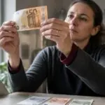Υπάλληλος σε ταμείο γερμανικού καταστήματος ελέγχει χαρτονόμισμα των 50 ευρώ στο φως