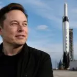 Ο Elon Musk μπροστά από εγκαταστάσεις διαστημικών εκτοξεύσεων με πύραυλο της SpaceX στο βάθος.
