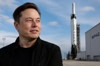 Ο Elon Musk μπροστά από εγκαταστάσεις διαστημικών εκτοξεύσεων με πύραυλο της SpaceX στο βάθος.