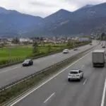 Κυκλοφορία αυτοκινήτων και φορτηγού σε ελβετικό αυτοκινητόδρομο με φόντο αλπικό τοπίο