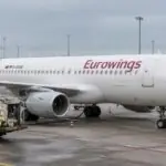Αεροσκάφος της Eurowings σε αεροδρόμιο, με όχημα ανεφοδιασμού και εργαζόμενο εδάφους δίπλα του.