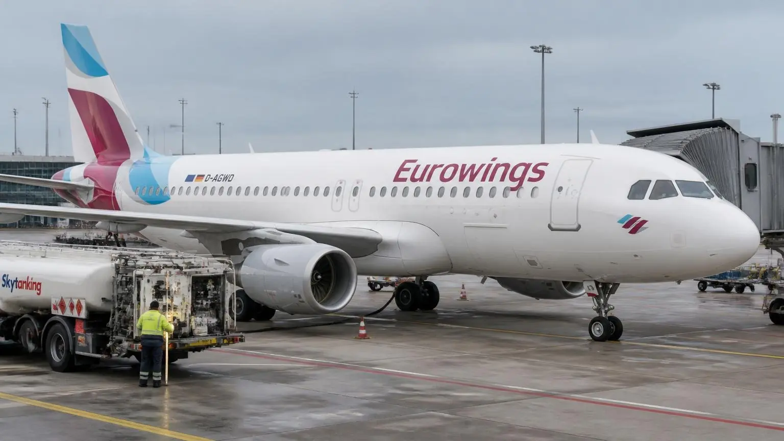 Αεροσκάφος της Eurowings σε αεροδρόμιο, με όχημα ανεφοδιασμού και εργαζόμενο εδάφους δίπλα του.