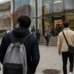 Φοιτητές με σακίδια περπατούν προς την είσοδο πανεπιστημιακού κτιρίου.