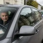 Συμβολική απεικόνιση μεσήλικα οδηγού μέσα σε αυτοκίνητο και αστυνομικού στο βάθος