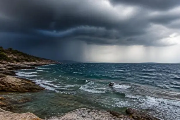 Dunkle Regenwolken über einer felsigen griechischen Küste und einer bewegten Meeresoberfläche.
