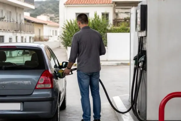 Eine Person betankt ein Auto an einer Tankstelle in einer mediterran geprägten Wohngegend.