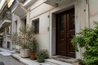 Eingang eines mehrstöckigen Wohnhauses mit Balkonen in einer griechischen Stadt.