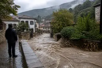 Schlammiges Hochwasser überflutet eine Dorfstraße in einer grünen griechischen Küstenlandschaft