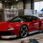 Κόκκινη Ferrari σε συμβολικό έλεγχο από τελωνειακούς σε χώρο αεροπορικού φορτίου.