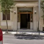 Symbolische Ansicht eines Wohnhauseingangs in Athen mit einem unscharfen Einsatzfahrzeug