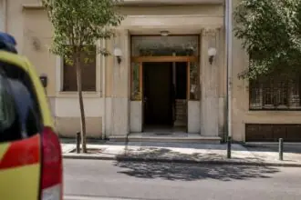 Symbolische Ansicht eines Wohnhauseingangs in Athen mit einem unscharfen Einsatzfahrzeug
