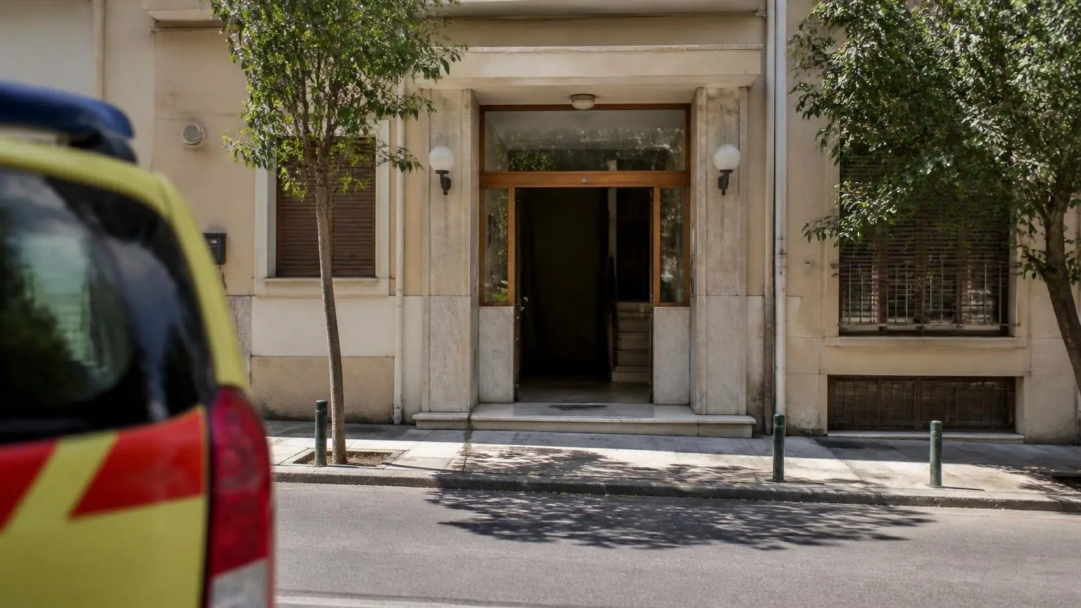 Symbolische Ansicht eines Wohnhauseingangs in Athen mit einem unscharfen Einsatzfahrzeug