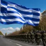 Griechische Flagge vor einer symbolisch dargestellten Militärparade zum Ochi-Tag