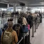 Ταξιδιώτες με αποσκευές περιμένουν σε ουρά μπροστά σε σημεία ελέγχου διαβατηρίων αεροδρομίου