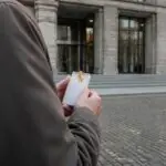 Άνδρας κρατά πακέτο τσιγάρα μπροστά από κτίριο δικαστηρίου στη Γερμανία.