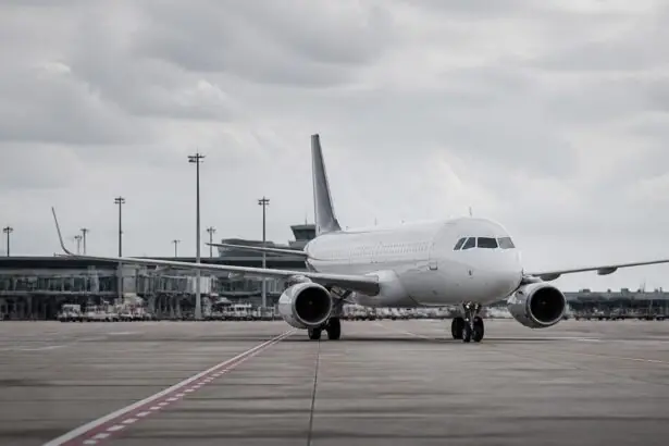 Ein Passagierflugzeug steht auf einem Flughafenvorfeld, im Hintergrund ist ein Terminal zu sehen.