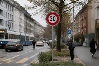 Πινακίδα ορίου ταχύτητας 30 χλμ./ώρα σε αστικό δρόμο της Ζυρίχης με οχήματα και πεζούς.