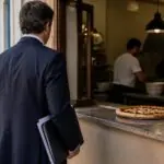 Symbolbild eines Pizza-Imbisses in Griechenland mit einer Person und Unterlagen