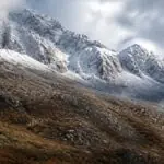 Symbolbild verschneiter Berggipfel über herbstlichen Hängen und Wolken auf Kreta