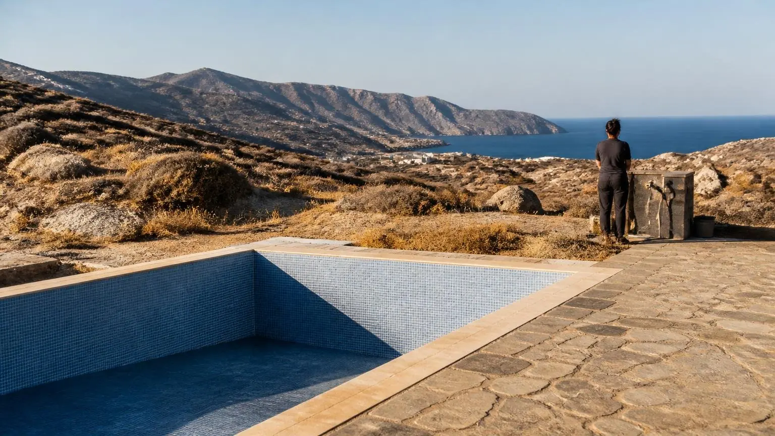 Symbolisches Schwimmbecken vor einer trockenen Landschaft auf einer griechischen Kykladeninsel