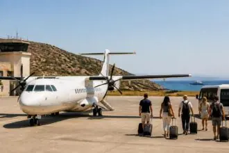 Reisende mit Gepäck neben einem Regionalflugzeug auf einem griechischen Inselflughafen, symbolische Darstellung