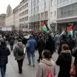 Πλήθος διαδηλωτών με πλακάτ και παλαιστινιακές σημαίες στο κέντρο γερμανικής πόλης, σε συμβολική εικόνα
