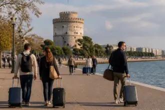 Symbolbild von Reisenden mit Koffern an der Uferpromenade von Thessaloniki mit dem Weißen Turm im Hintergrund