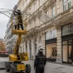 Τεχνικός σε ανυψωτικό όχημα τοποθετεί χριστουγεννιάτικη διακόσμηση πάνω από εμπορικό δρόμο της Βιέννης.