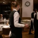 Εργαζόμενος σε γερμανικό εστιατόριο μεταφέρει πιάτα κατά τη διάρκεια βραδινής βάρδιας.