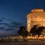 Symbolbild des abends beleuchteten Weißen Turms an der Uferpromenade von Thessaloniki