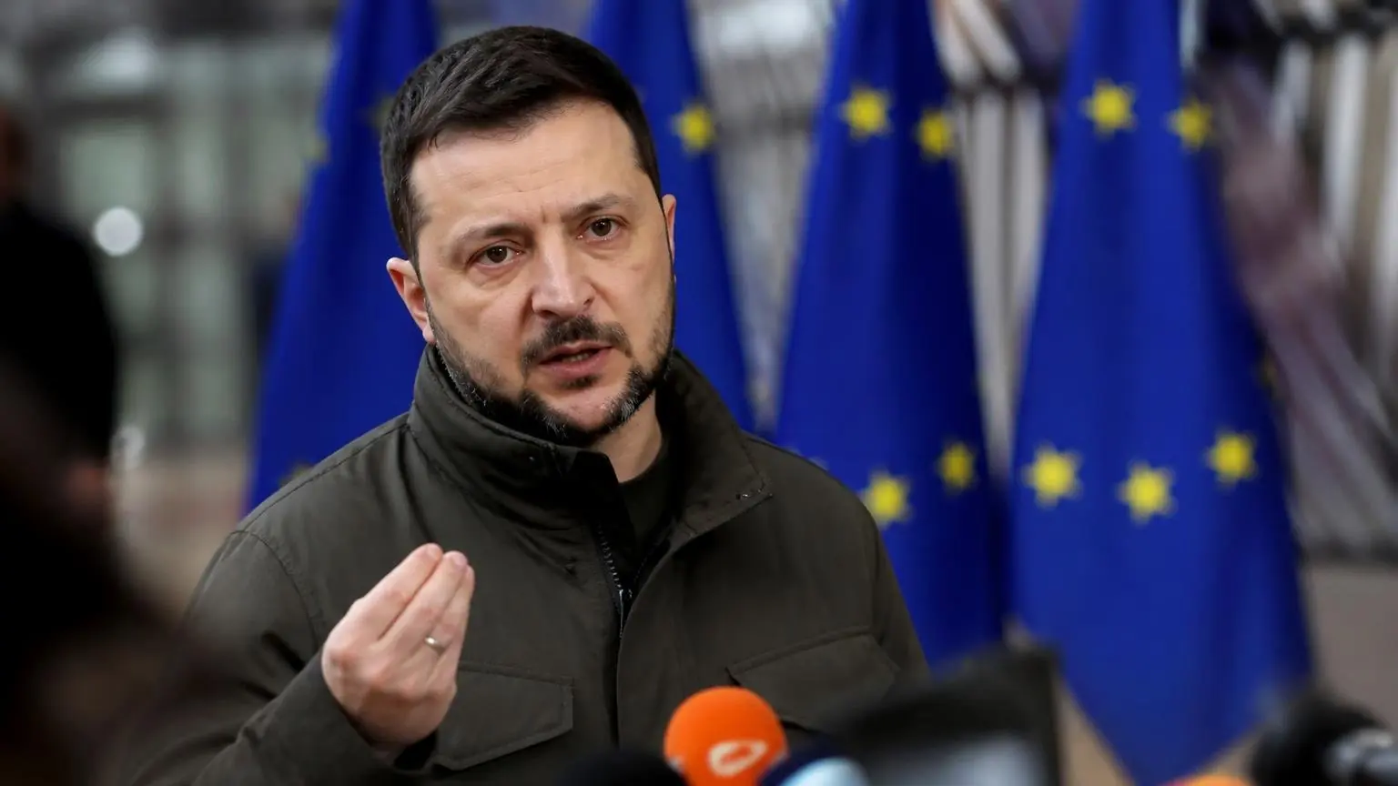 Ο Βολοντίμιρ Ζελένσκι μιλά σε δημοσιογράφους με σημαίες της ΕΕ στο φόντο.